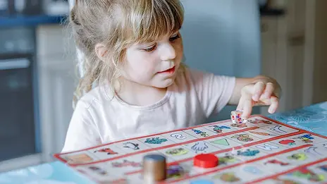 Ein Mädchen spielt ein Brettspiel. 