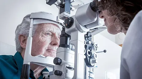 Eine Mitarbeiterin der Augenheilkunde führt einen Test bei einem Patienten durch. 