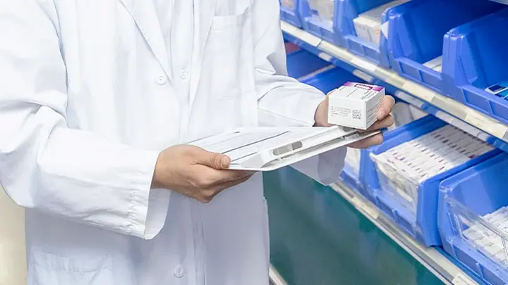 Ein Apotheker hält eine Medikamentenpackung in der Hand. 