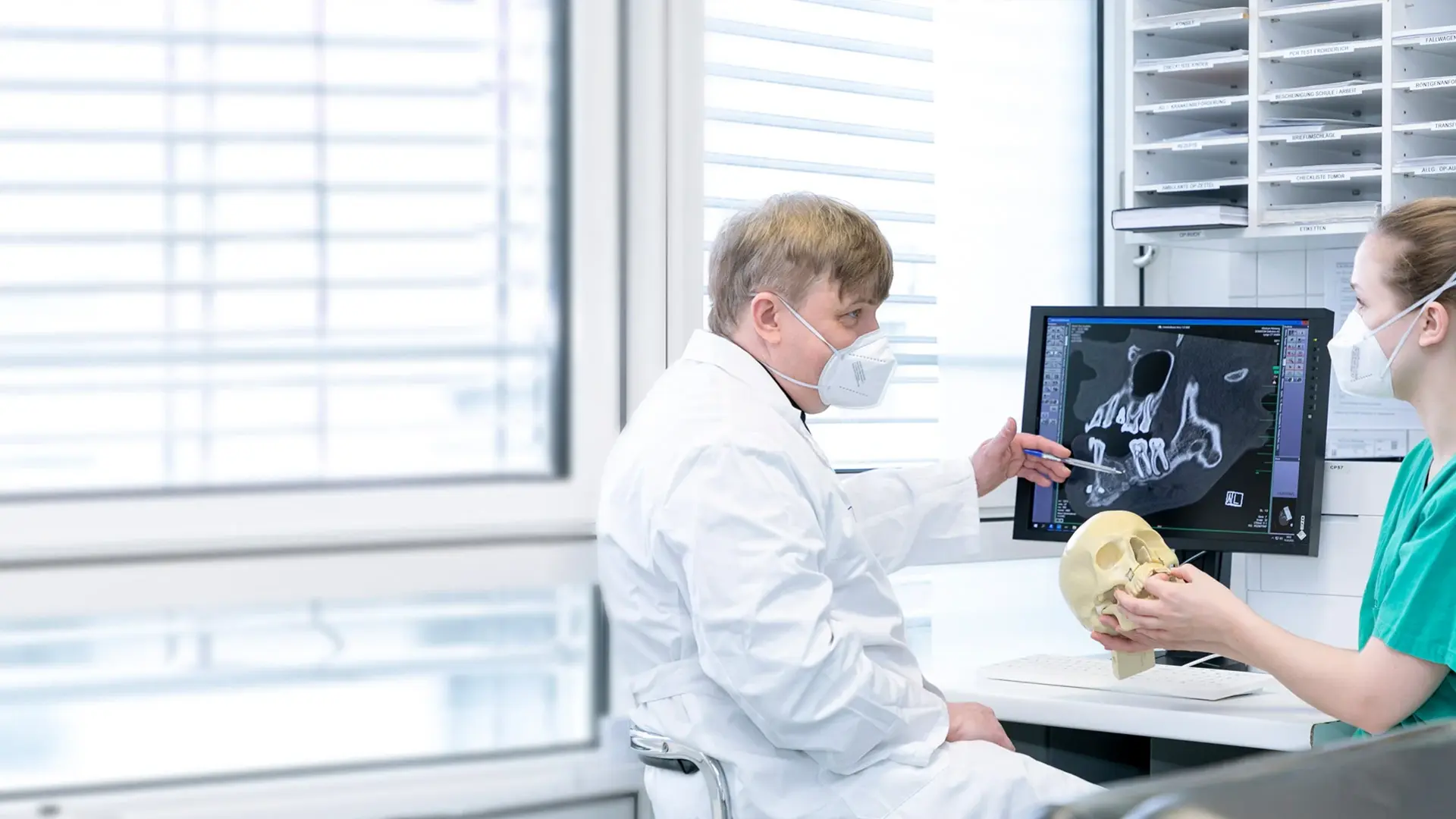 Prof. Dr. Dr. Alexander Eckert, Chefarzt, und eine Mitarbeiterin legen gemeinsam einen Verband an.