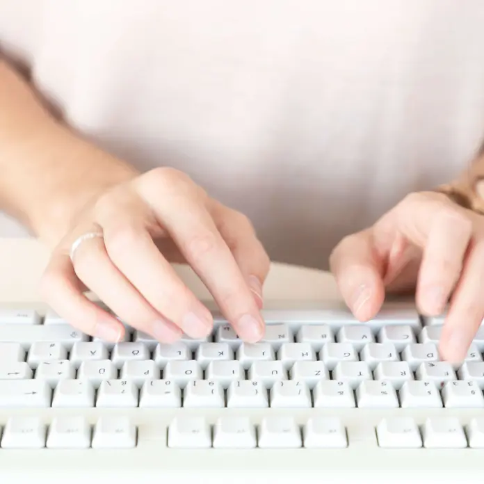 Das Symbolbild zeigt die Hände einer Frau. Sie tippt auf einer Computer-Tastatur. 