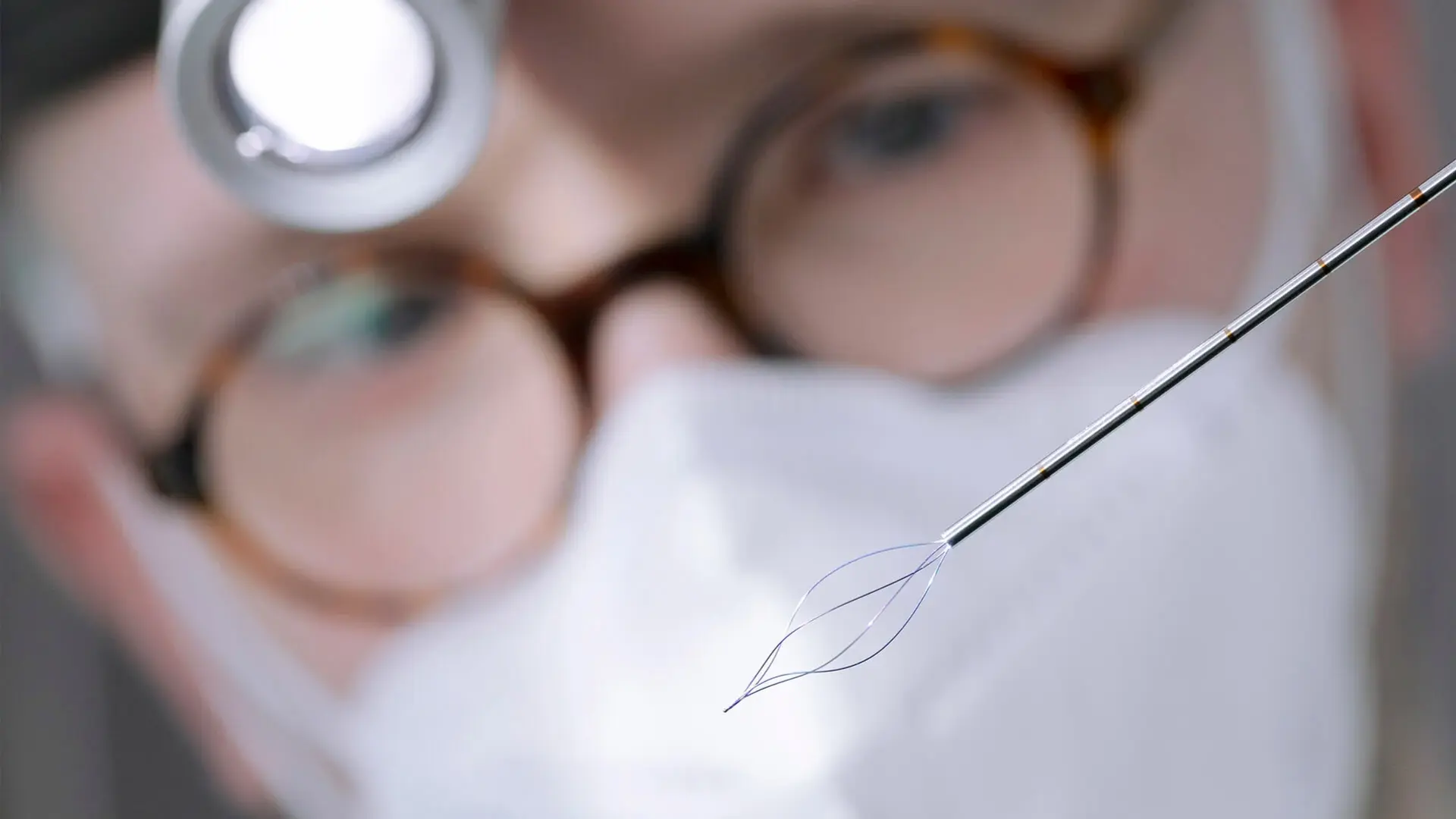 Arzt betrachtet eine Sonde mit einer Lupenbrille