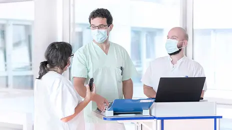 Drei Mitarbeitende besprechen Patientendaten. 