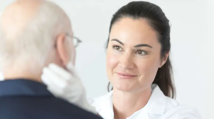 Ärztin untersucht Patienten am Hals