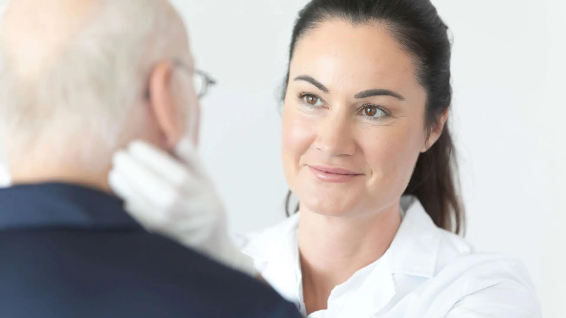 Ärztin untersucht Patienten am Hals
