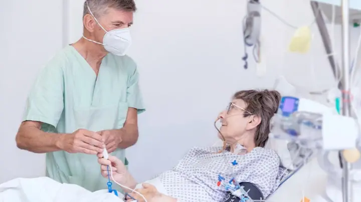 Oberarzt, Dr. Dirk Risack spricht mit einer Patientin im Bett.  