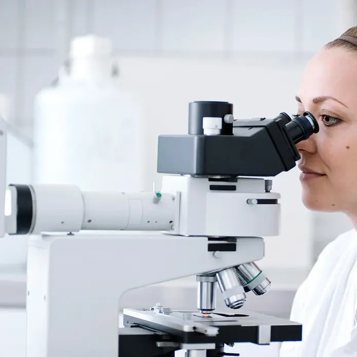 Eine Mitarbeiterin der Pathologie untersucht Gewebeproben unter dem Mikroskop.