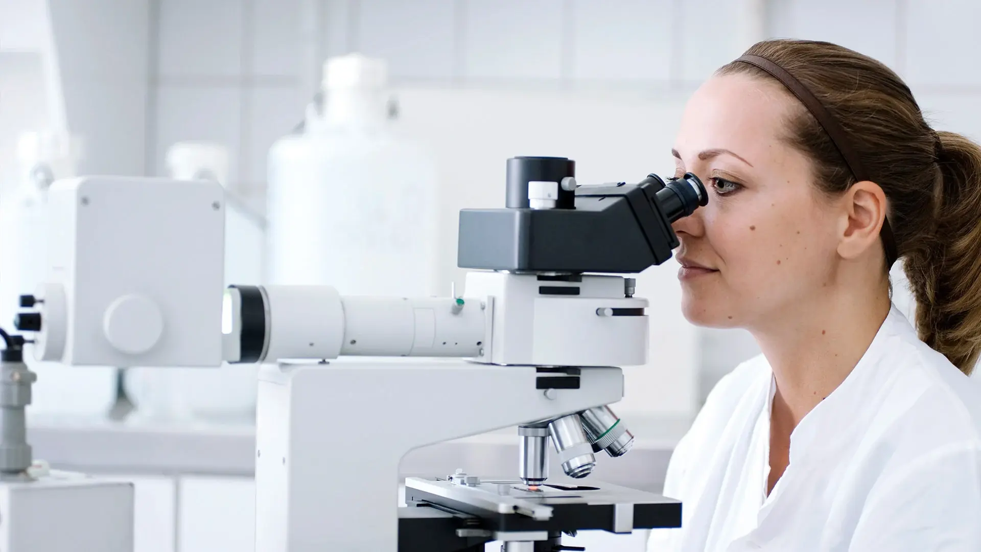 Eine Mitarbeiterin der Pathologie untersucht Gewebeproben unter dem Mikroskop.