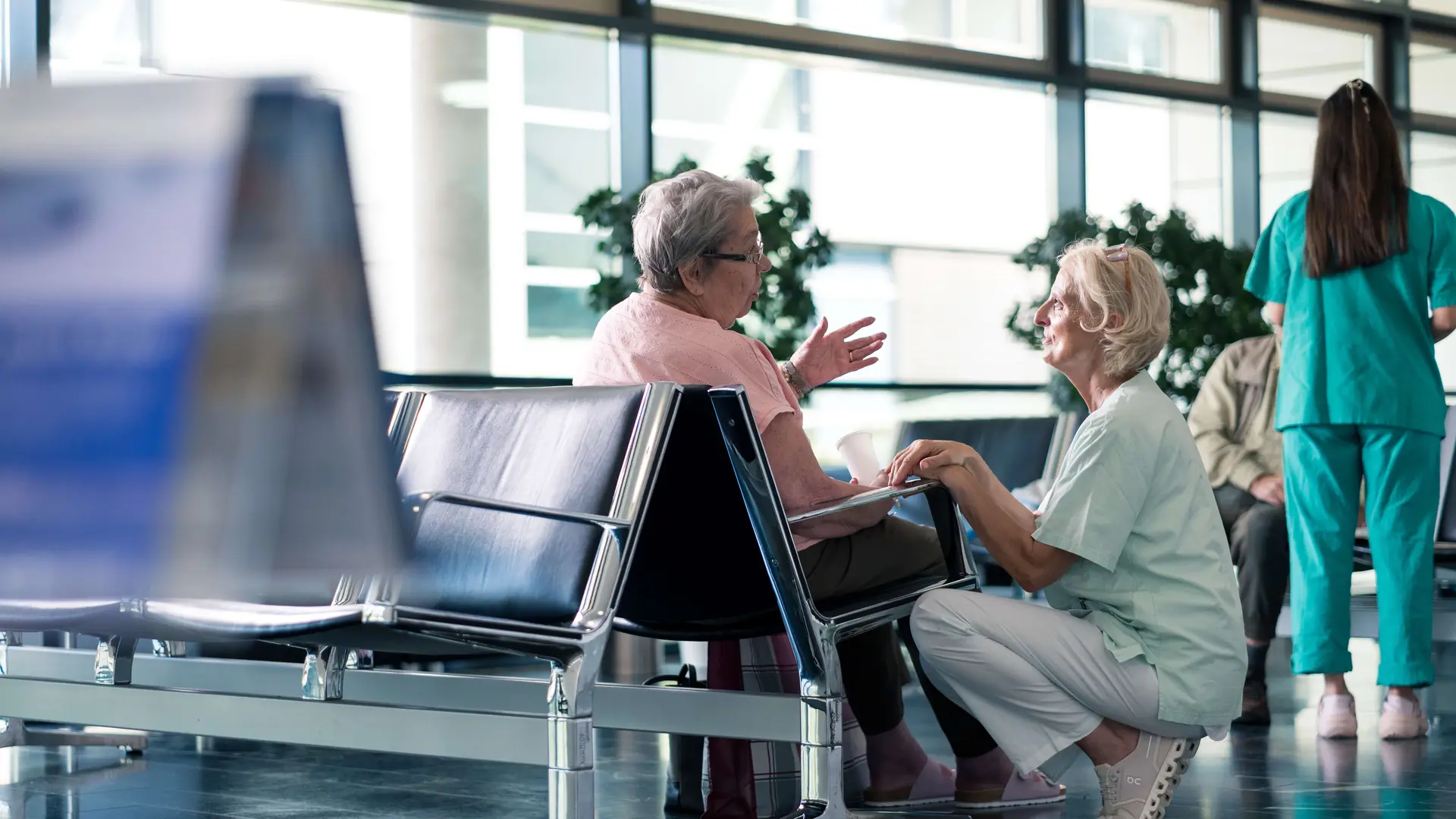 Eine Kollegin kniet neben einer Patienten und spricht mit ihr. 