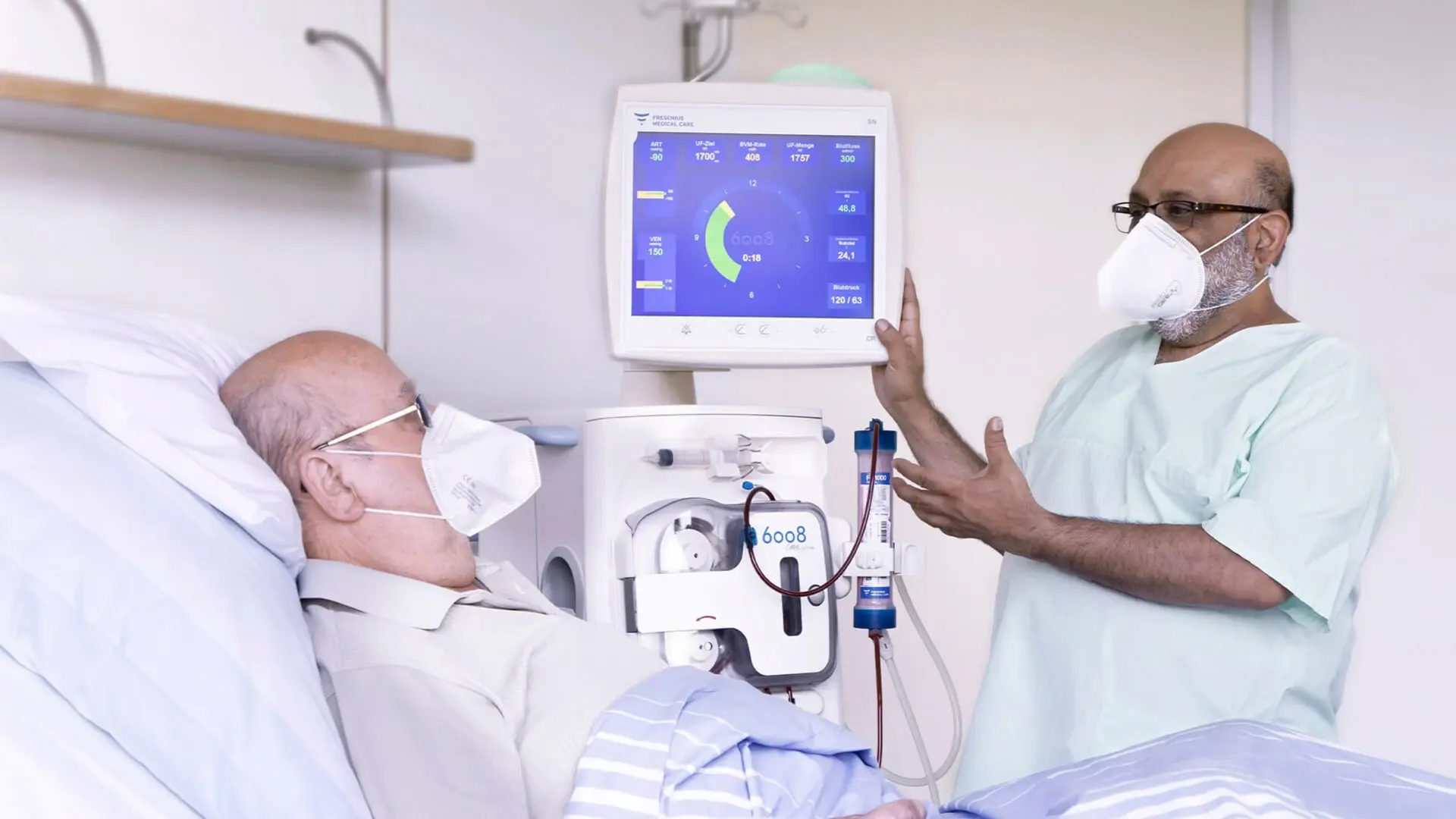 Ein Mitarbeiter der Nephrologie spricht mit einem Patienten im Bett. 