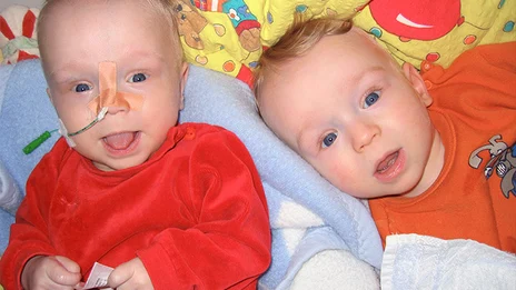 Die Babys Niels und Tom liegen zusammen auf einer Kuscheldecke. 