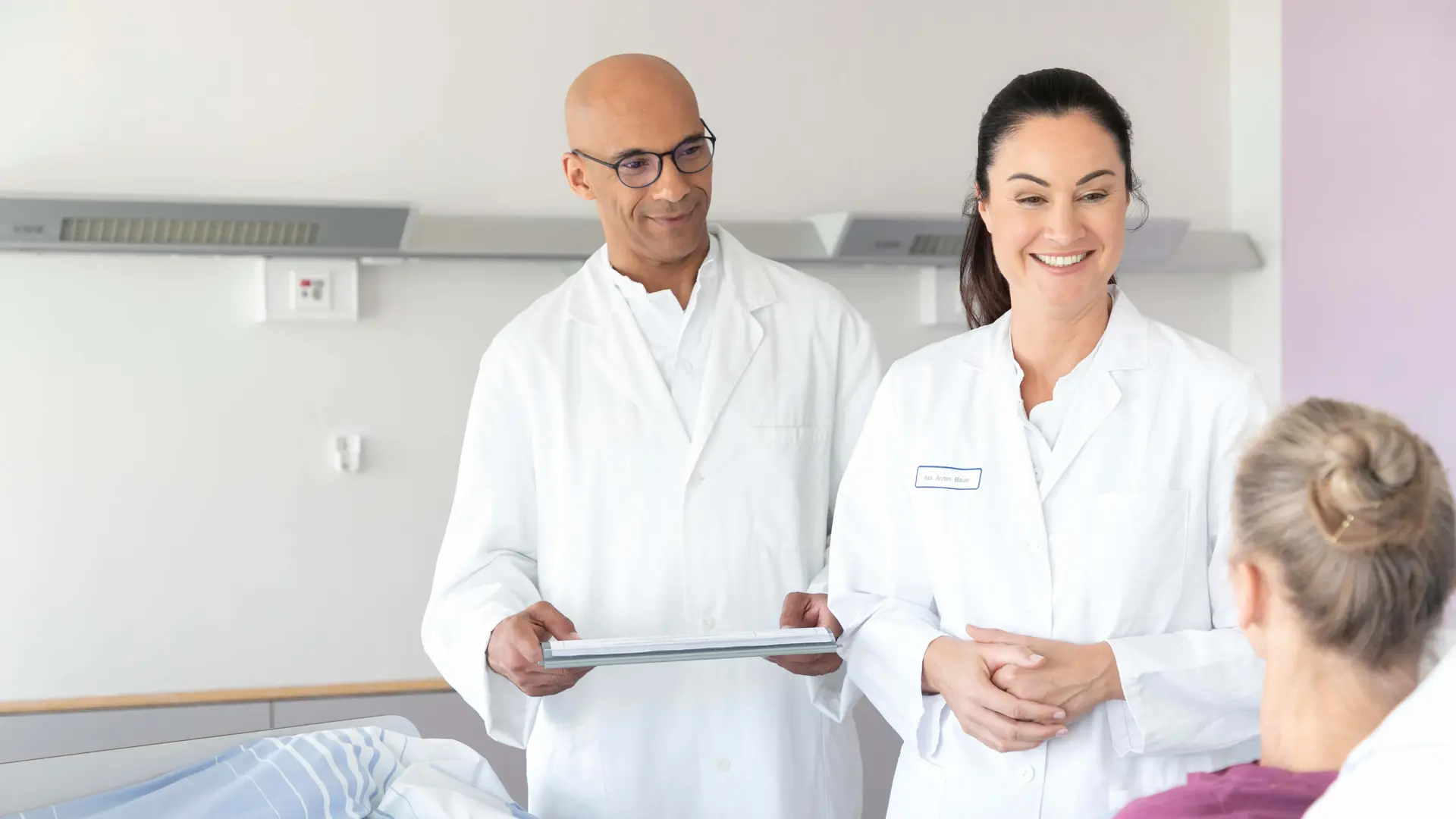 Zwei Ärzte unterhalten sich mit einer Patientin im Bett