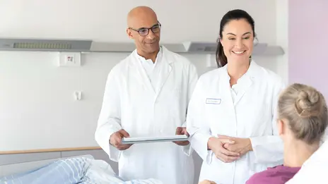 Zwei Ärzte unterhalten sich mit einer Patientin im Bett