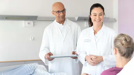 Zwei Ärzte unterhalten sich mit einer Patientin im Bett