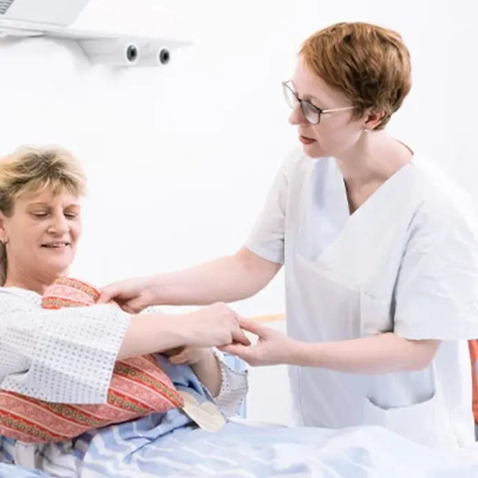  Eine Mitarbeiterin legt einer Brustkrebspatientin ein Herzkissen unter den Arm 