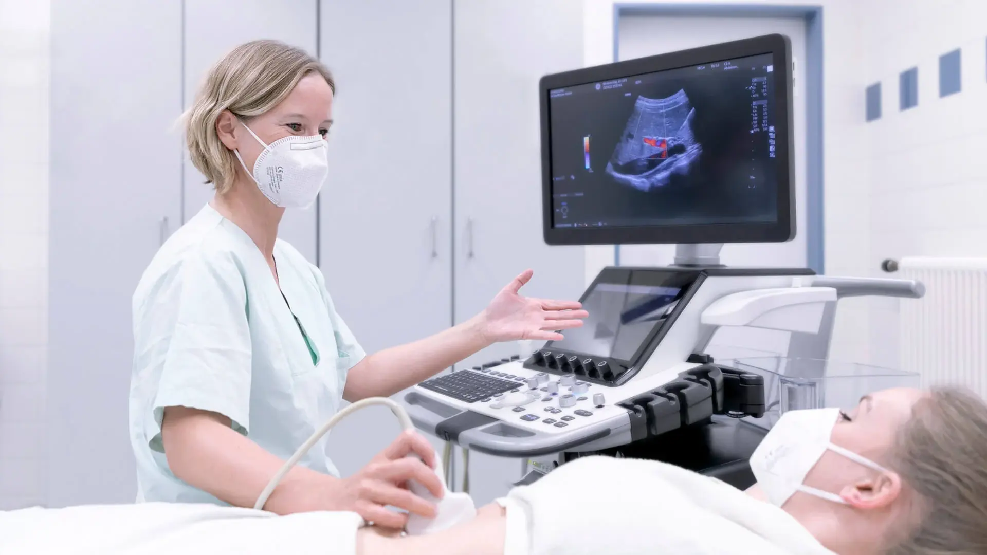 Eine Mitarbeiterin der Gastroenterologie für eine Ultraschalluntersuchung am Bauch eines Patienten durch.