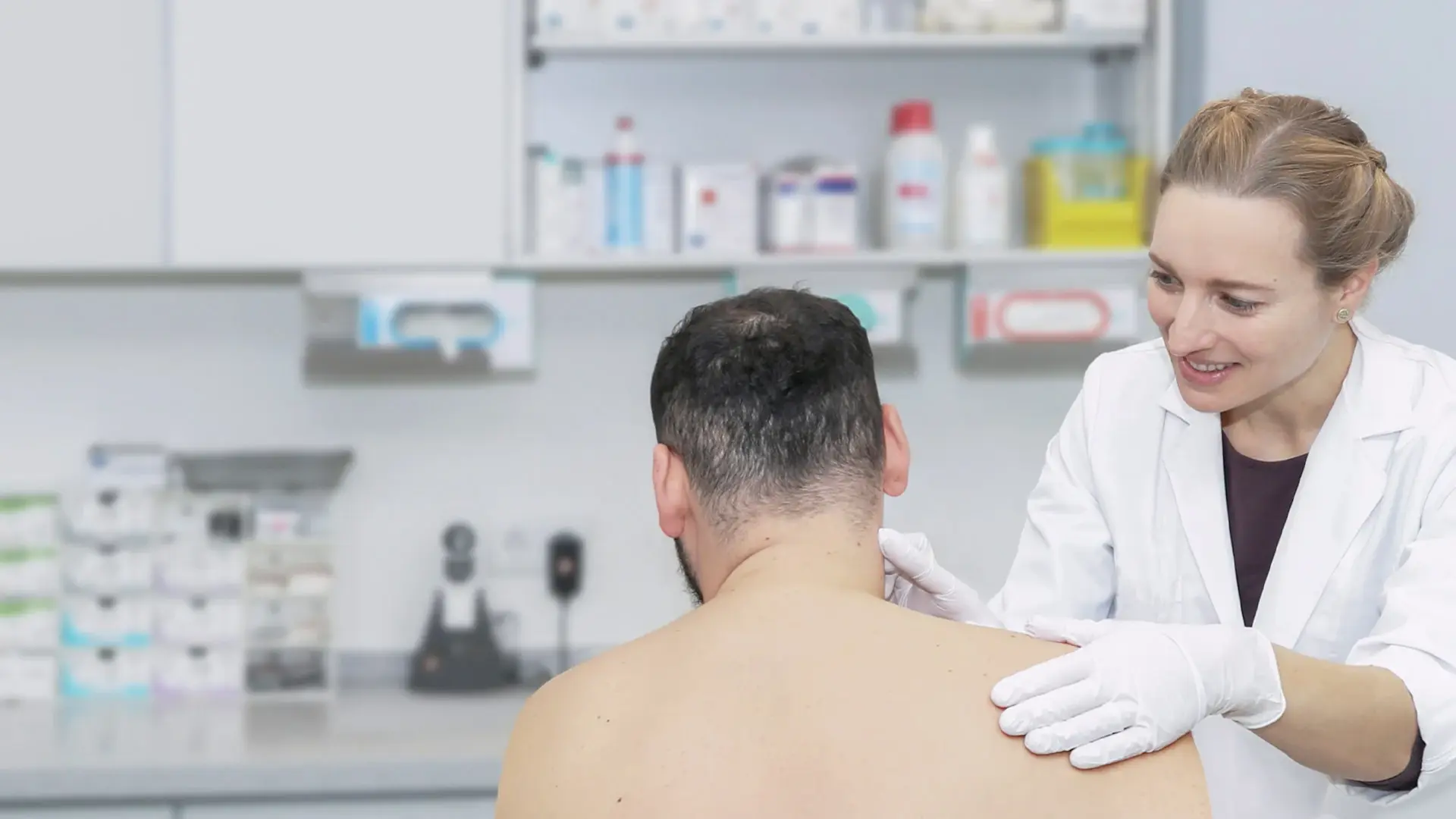 Eine Mitarbeiterin der Hautklinik untersucht die Haut eines Patienten am Hals. 