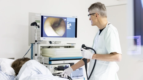 Ein Mitarbeitender der Gastroenterologie untersucht eine schlafende Patientin.