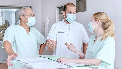 Drei Mitarbeitende besprechen Patientendaten. 