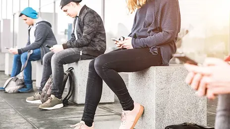 Drei Jugendliche mit Handy in der Hand während der Medientherapie