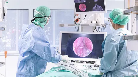 Zwei Mitarbeitende schauen während eines Eingriffs auf einen Monitor. 