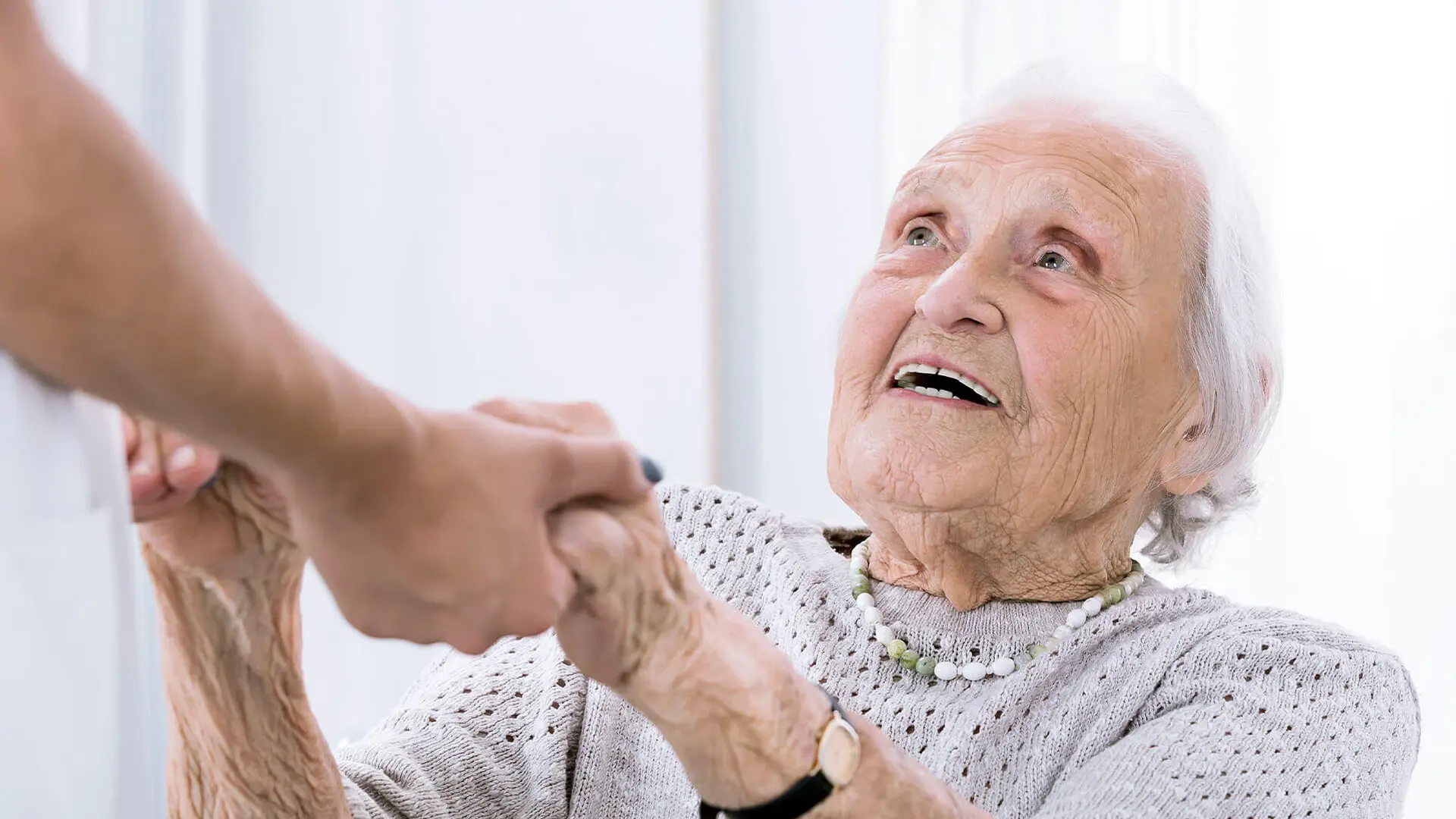 Das Symbolbild zeigt eine ältere Dame. Sie hält Händchen mit einem Mitarbeitenden des Zentrums für Alterstraumatologie. 