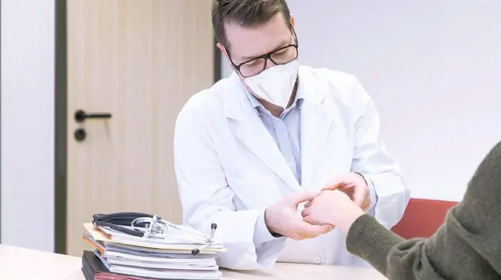 Ein Rheumatologe untersucht eine Patientin.