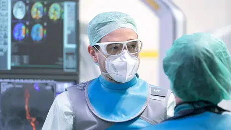 Dr. Florian Eff, Oberarzt, spricht mit einer Mitarbeiterin. Sie stehen vor einem Monitor. 