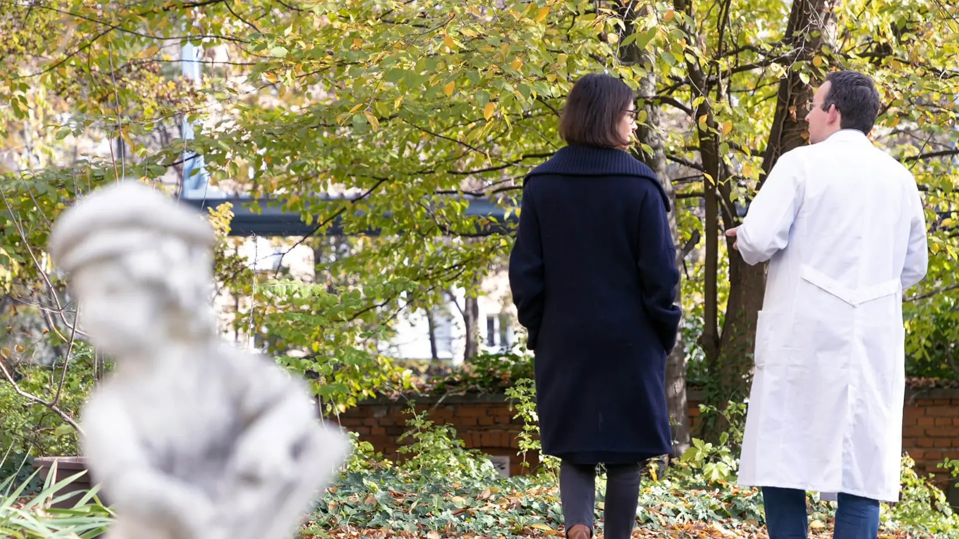 Eine Patientin mit Depressionen spricht mit einem Arzt der Psychiatrie. Sie gehen im Freien spazieren. 