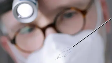 Arzt betrachtet eine Sonde mit einer Lupenbrille