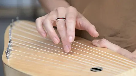 Eine Patientin spielt auf einer Kantele. 