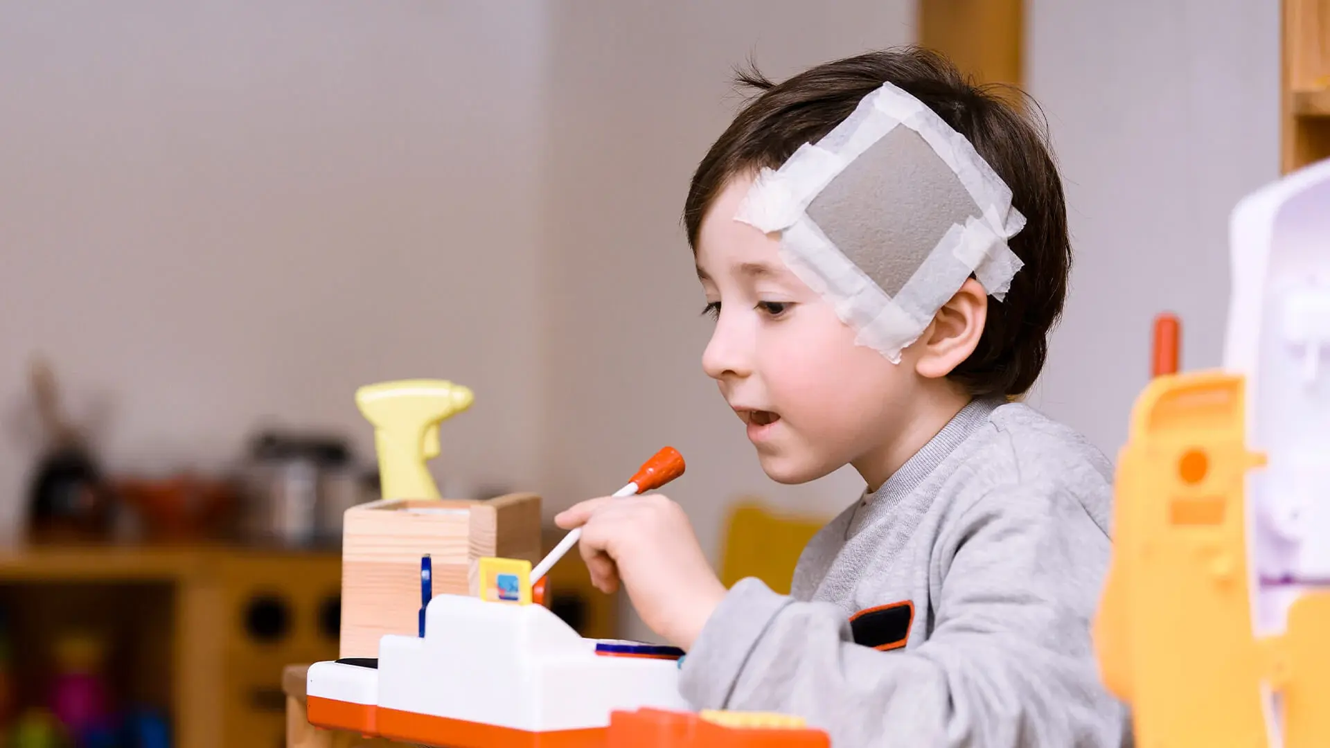 Der damals 5-jährige Giovanni spielt in der Kinderklinik. Er hat ein großes Pflaster am Kopf.