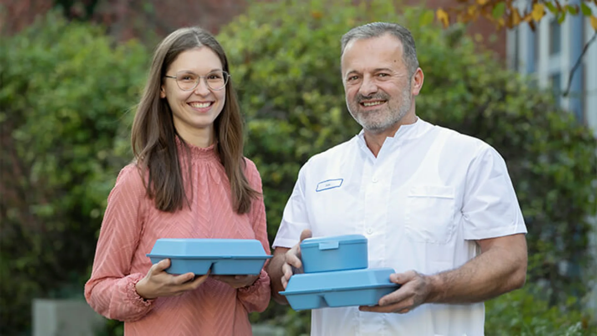 Zwei Kollegen halten die blaue Vesperbox in der Hand. 