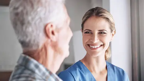 Eine Logopädin lächelt ihren Patienten freundlich an.