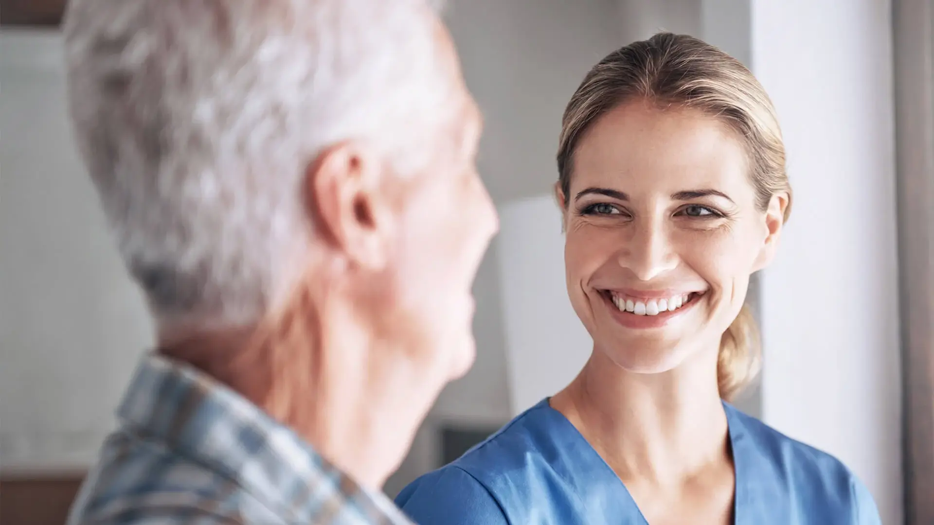Eine Logopädin lächelt ihren Patienten freundlich an.