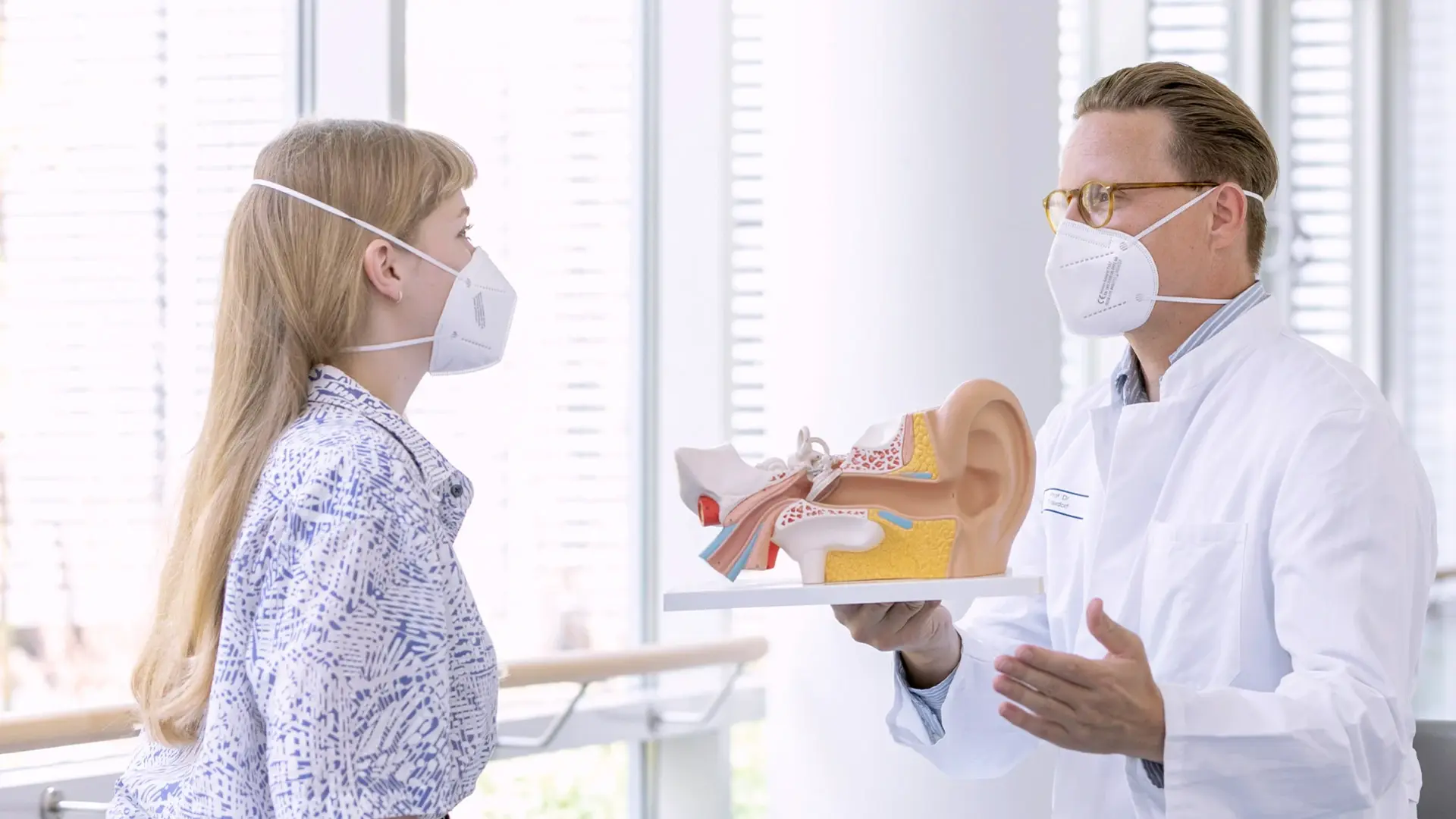 Prof. Dr. Maximilian Traxdorf, Chefarzt, erklärt einer Patientin die Diagnose anhand eines Ohren-Modells. 