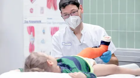 Dr. Sebastian Huber legt einem kleinen Jungen einen Gips am Bein an. 