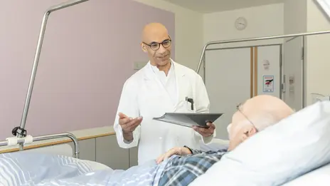 Ein Arzt spricht mit einem Patienten im Bett.