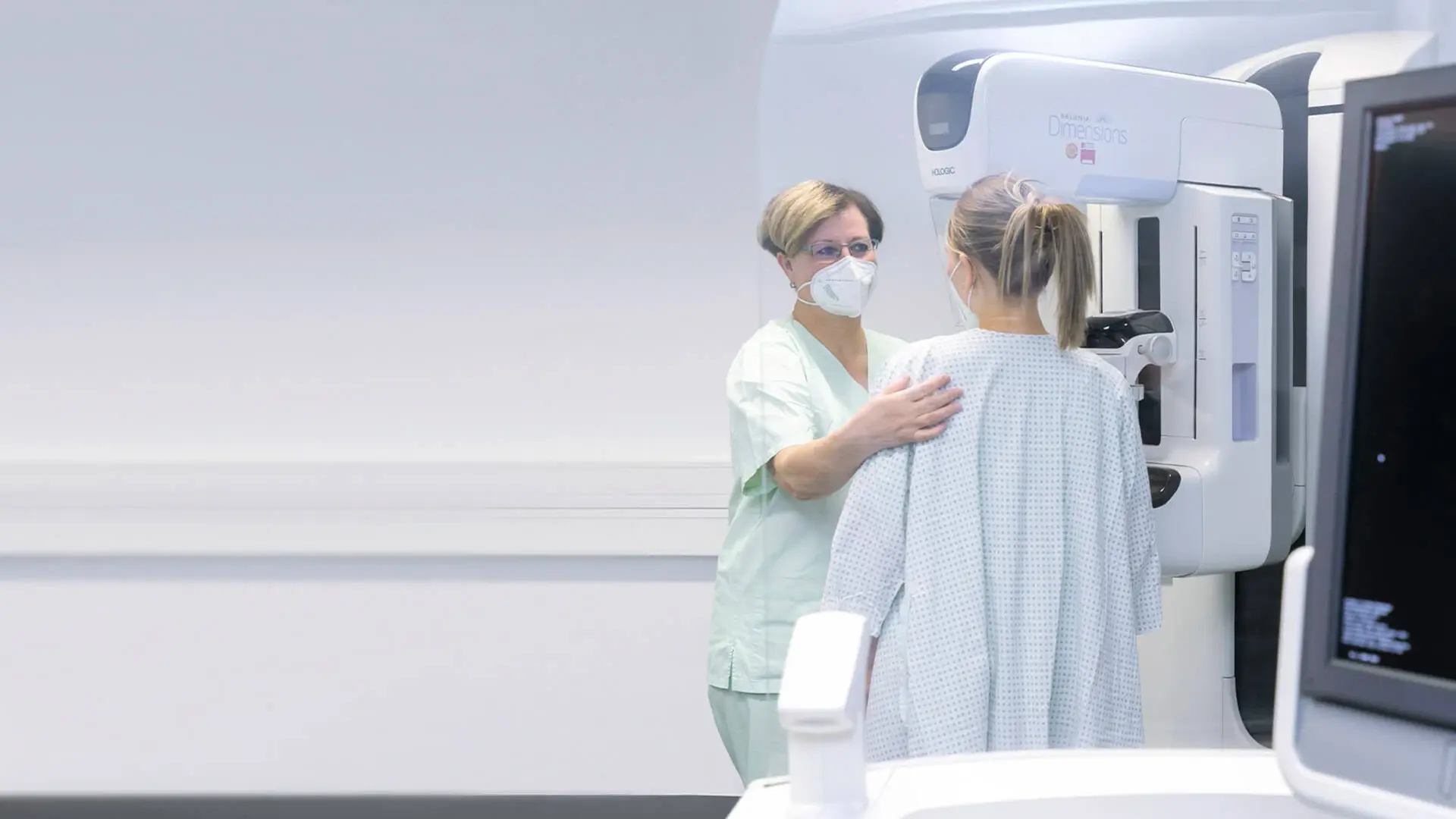Eine Mitarbeiterin der Radiologie bereitet eine Patientin auf die Mammographie vor. 