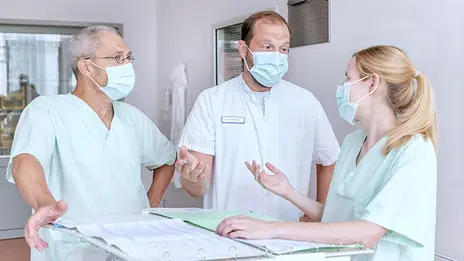 Drei Mitarbeitende besprechen Patientendaten. 