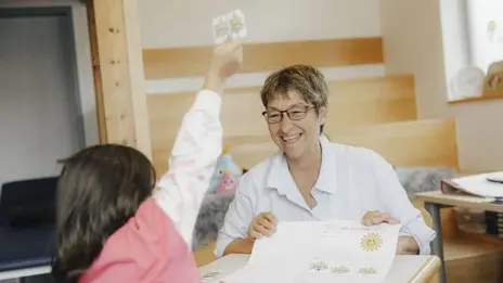 Eine Kollegin spielt mit einem jungen Mädchen ein Spiel. Die Stimmung ist positiv.