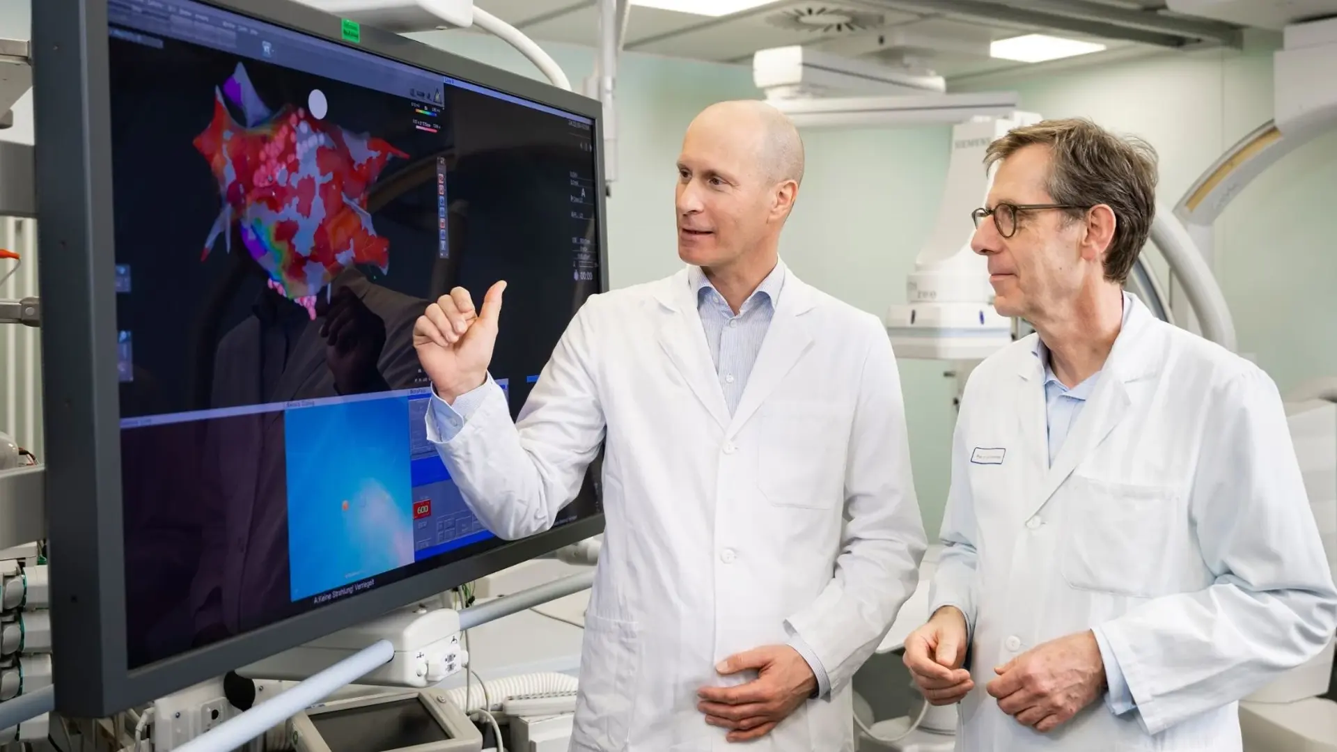 Zwei Ärzte stehen vor einem großen Monitor und besprechen sich