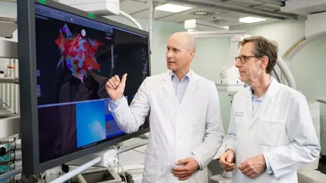 Zwei Ärzte stehen vor einem großen Monitor und besprechen sich