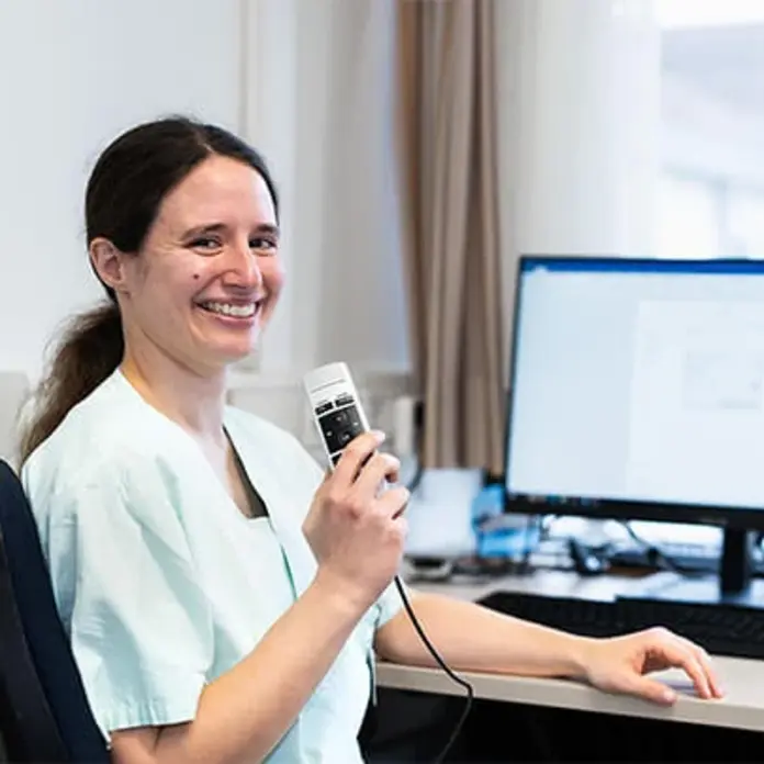 Eine Ärztin spricht in das Gerät zur Spracherkennung.  