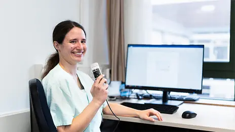 Eine Ärztin spricht in das Gerät zur Spracherkennung.  