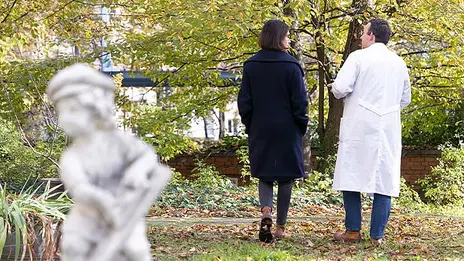 Eine Patientin mit Depressionen spricht mit einem Arzt der Psychiatrie. Sie gehen im Freien spazieren. 