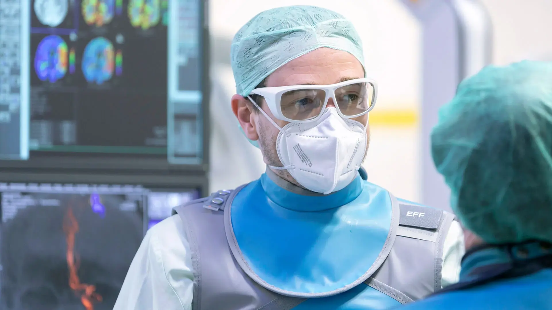 Dr. Florian Eff, Oberarzt, spricht mit einer Mitarbeiterin. Sie stehen vor einem Monitor. 