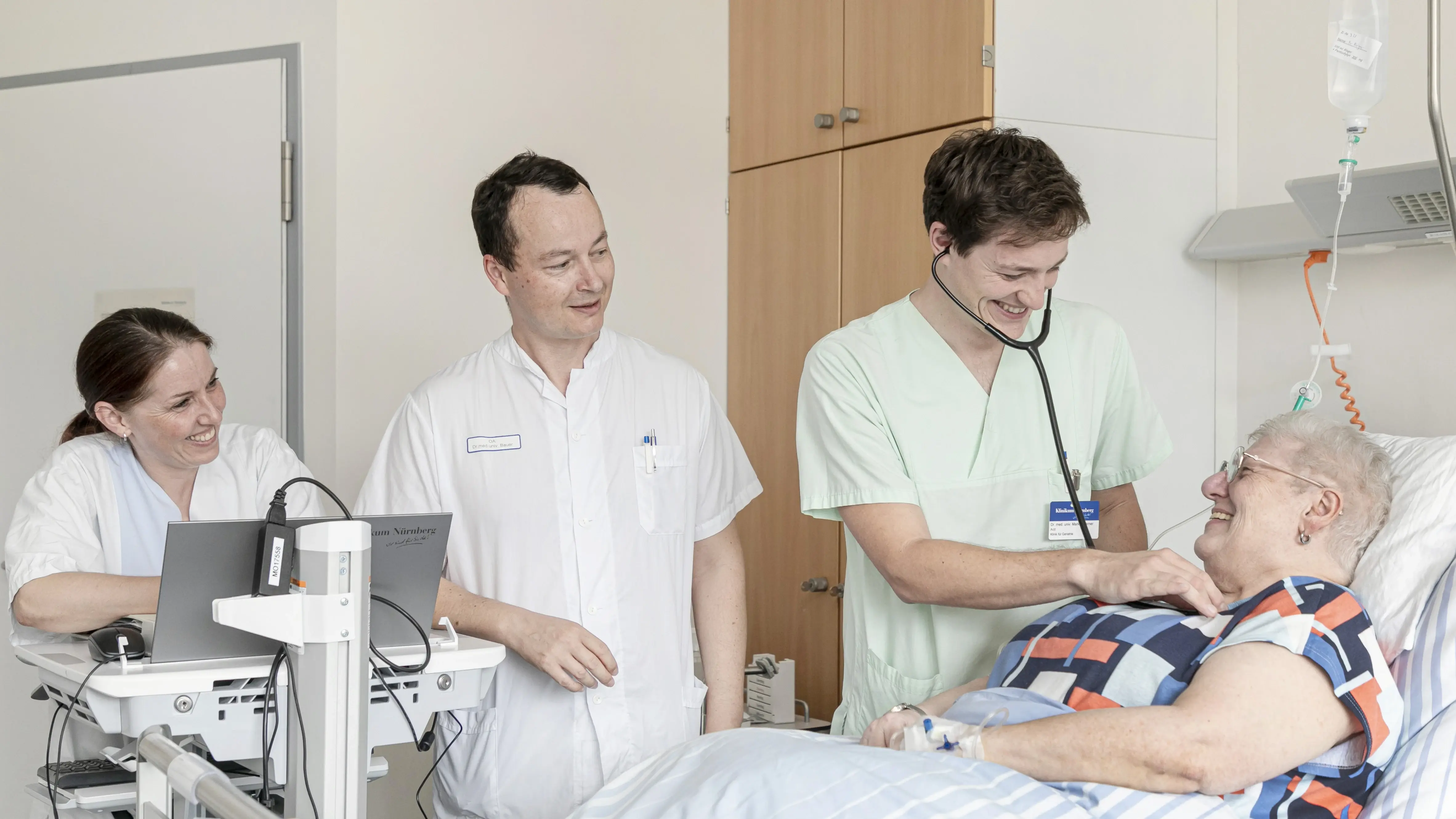 Ein interdisziplinäres Team kümmert sich um eine Patientin. Sie liegt im Bett.