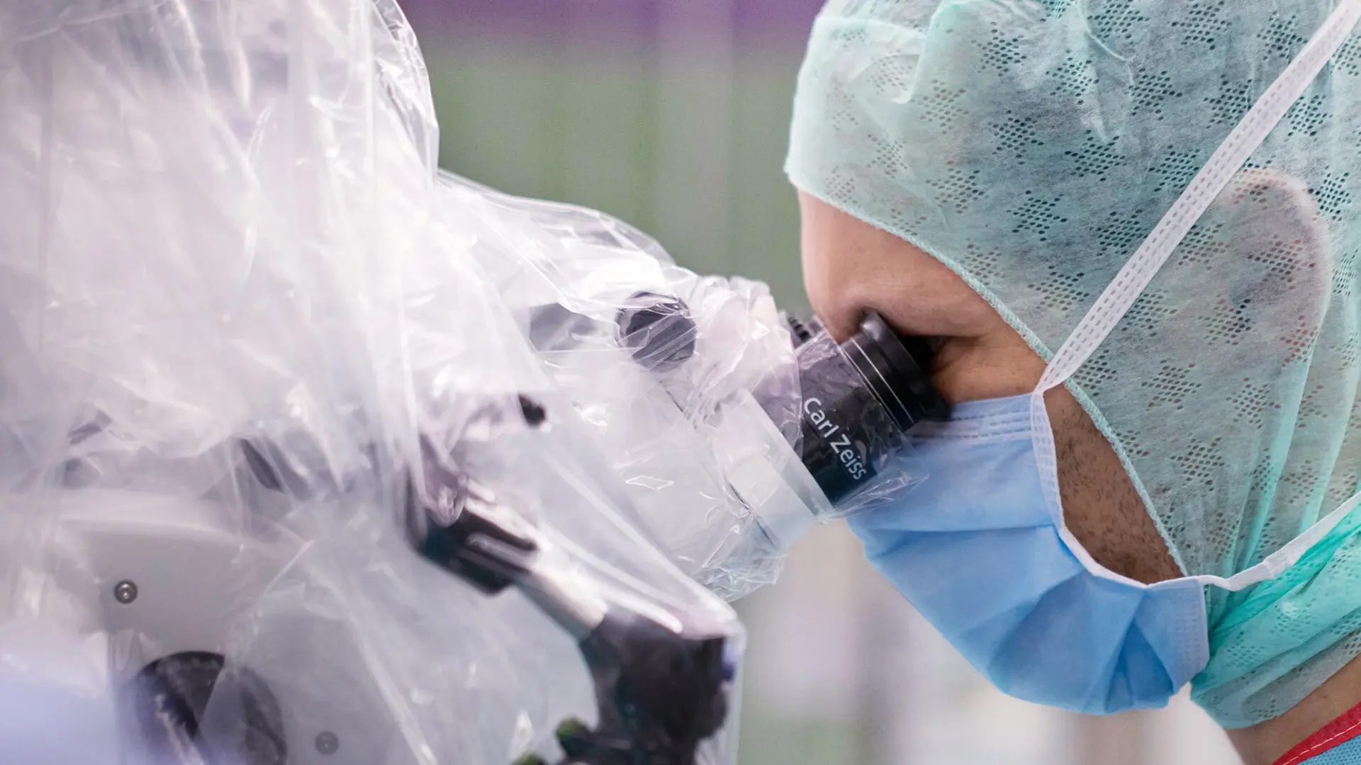 Dr. Michael Schrey, Oberarzt, schaut durch ein Mikroskop. Er befindet sich im OP. 