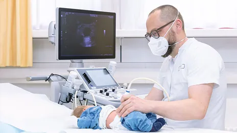 Ein Arzt führt eine Ultraschall Untersuchung am Bauch eines Babys durch